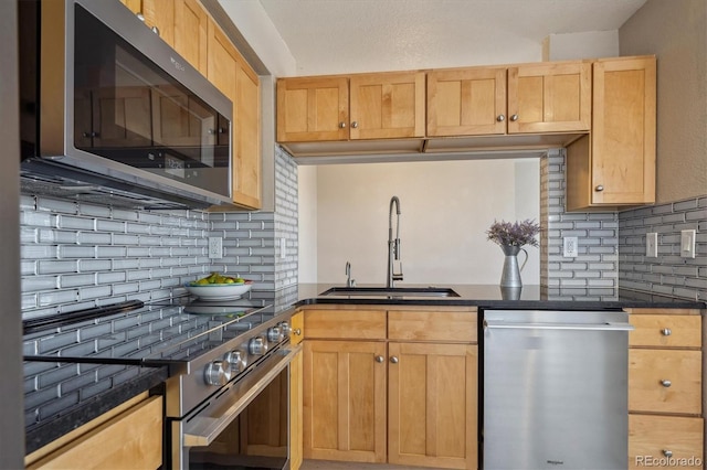 kitchen featuring a sink, dark countertops, backsplash, and stainless steel appliances