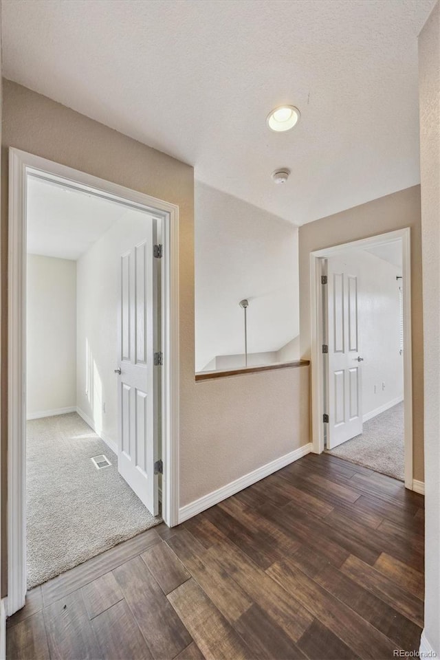 corridor featuring wood finished floors, visible vents, and baseboards