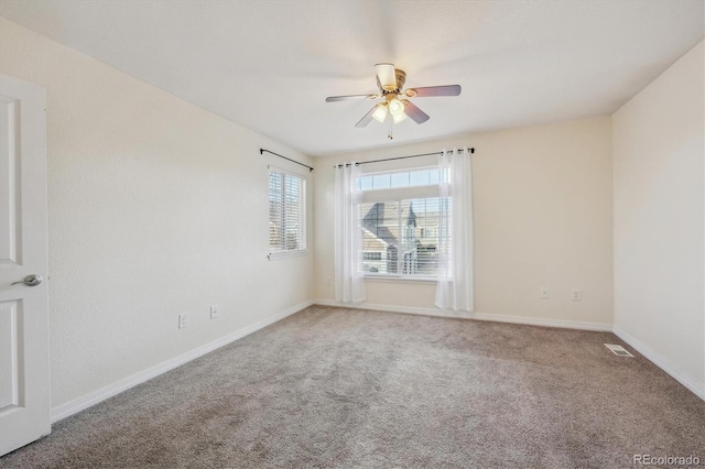 carpeted empty room with baseboards, visible vents, and ceiling fan