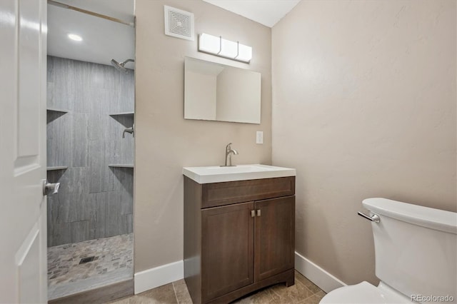 full bathroom with vanity, toilet, visible vents, and a tile shower