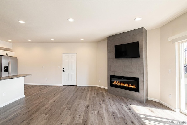 unfurnished living room featuring a tile fireplace and light wood-type flooring