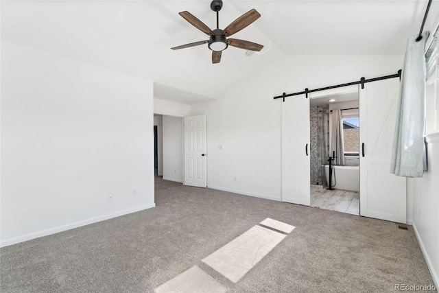 2430 S Halifax Way, Aurora, CO 80013 - unfurnished bedroom with carpet flooring, vaulted ceiling, a barn door, connected bathroom, and ceiling fan