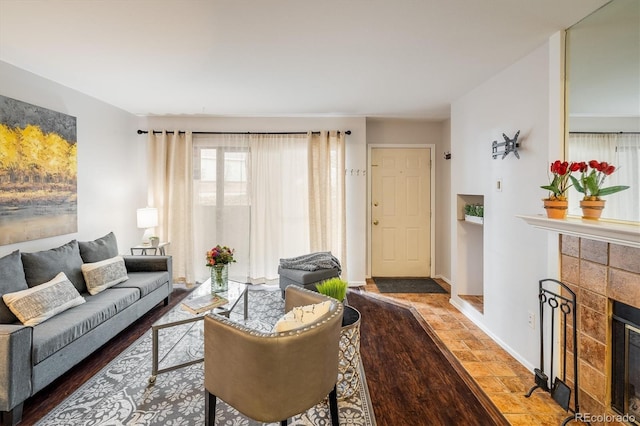 living area featuring baseboards, wood finished floors, and a tile fireplace