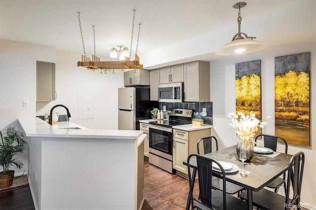 kitchen featuring dark wood-style flooring, a sink, appliances with stainless steel finishes, gray cabinets, and backsplash