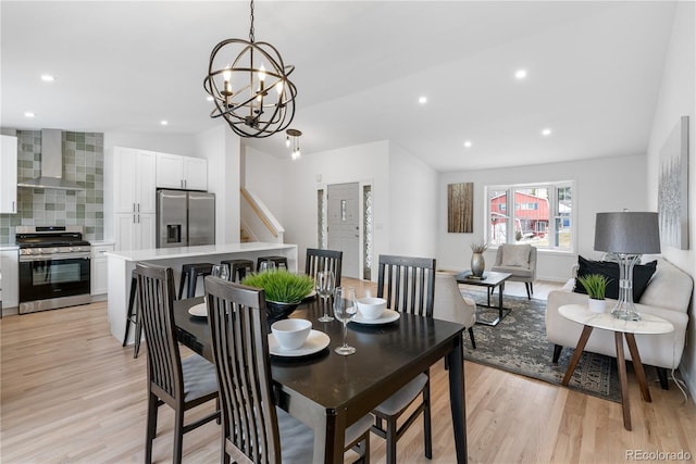 dining space with light hardwood / wood-style floors, vaulted ceiling, and an inviting chandelier