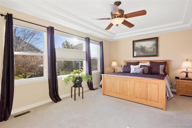 carpeted bedroom featuring ceiling fan and a raised ceiling