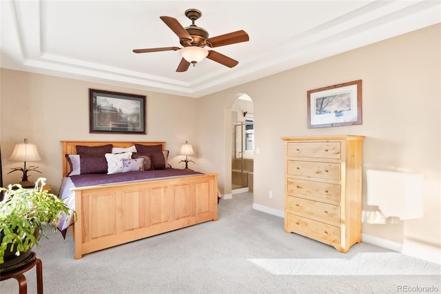 carpeted bedroom with a raised ceiling and ceiling fan