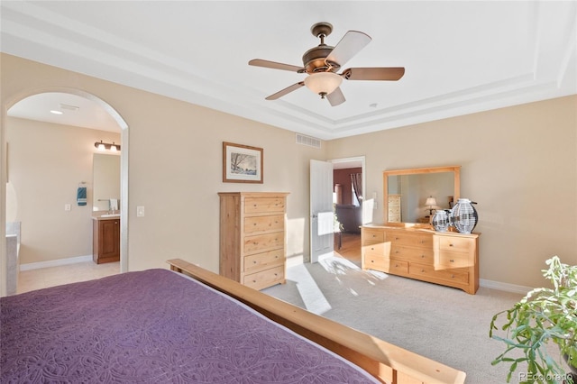 carpeted bedroom with ceiling fan and a raised ceiling