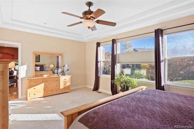 bedroom with multiple windows, carpet, a tray ceiling, and ceiling fan