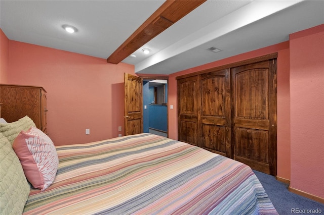 carpeted bedroom with a closet and beamed ceiling