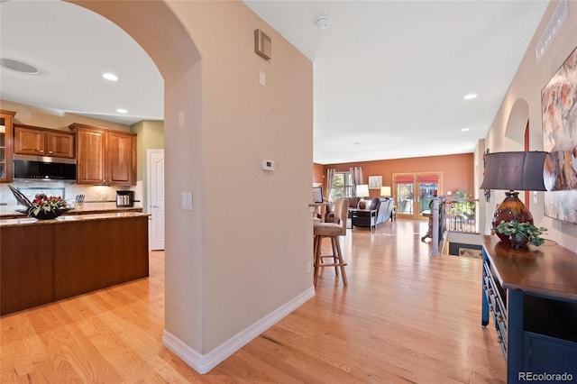 kitchen with light hardwood / wood-style floors, a kitchen bar, and backsplash