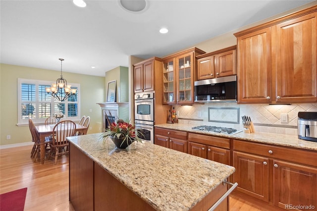 kitchen featuring stainless steel appliances, decorative backsplash, light hardwood / wood-style floors, pendant lighting, and a center island