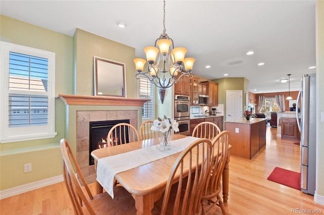 dining room with a tile fireplace, light hardwood / wood-style floors, and a chandelier