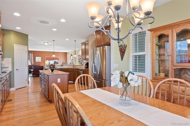 dining area featuring a notable chandelier, light hardwood / wood-style flooring, and sink