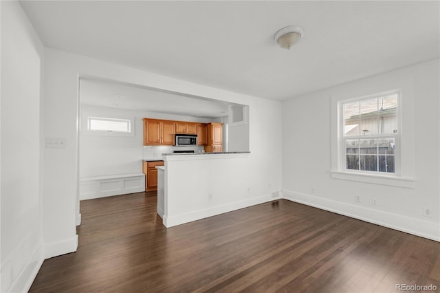 unfurnished living room with a healthy amount of sunlight and dark wood-type flooring