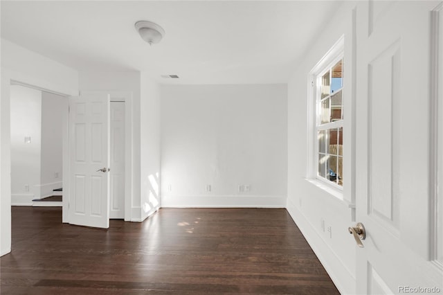 spare room featuring a wealth of natural light and dark hardwood / wood-style flooring