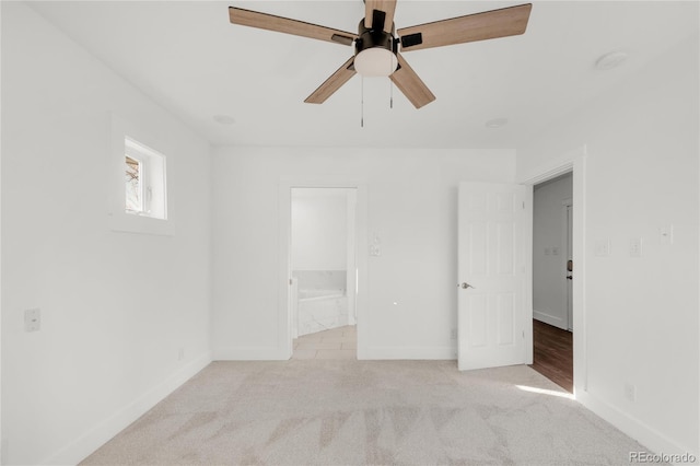 unfurnished bedroom with ceiling fan, light colored carpet, and ensuite bath