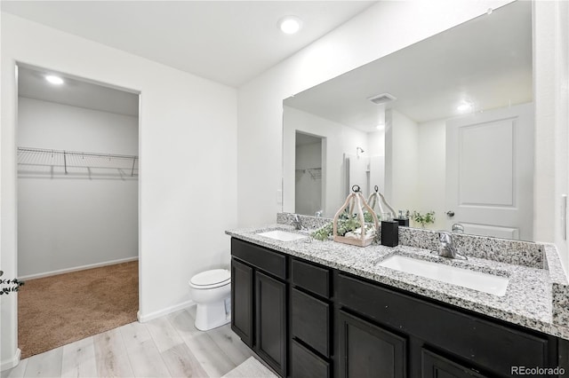 9723 Borderpine Way, Colorado Springs, CO 80925 - bathroom with double vanity, wood finished floors, a spacious closet, and recessed lighting