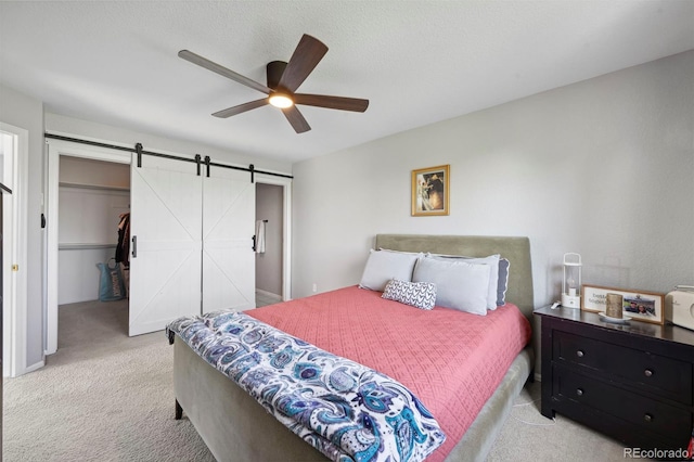 7977 Emerson Ave, Frederick, CO 80530 - bedroom featuring light carpet, a barn door, a spacious closet, and a ceiling fan