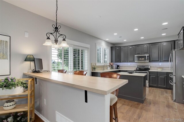 15372 E 117th Ave, Commerce City, CO 80022 - kitchen with appliances with stainless steel finishes, a center island, light wood-style floors, healthy amount of natural light, and recessed lighting