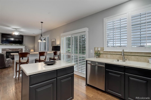 15372 E 117th Ave, Commerce City, CO 80022 - kitchen featuring stainless steel dishwasher, open floor plan, a ceiling fan, a fireplace, and wood finished floors