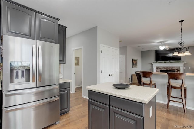 15372 E 117th Ave, Commerce City, CO 80022 - kitchen featuring stainless steel fridge, light wood-type flooring, a ceiling fan, and a fireplace