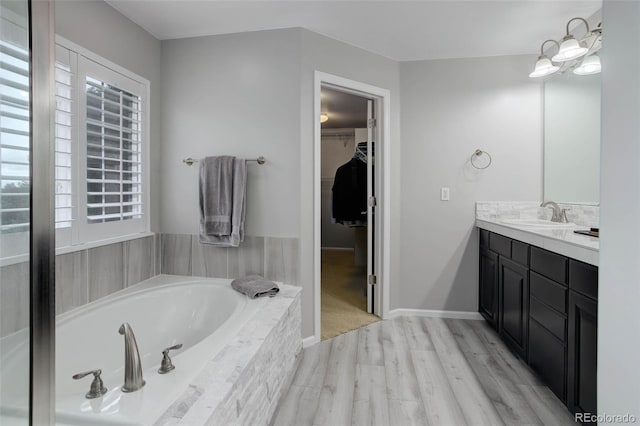 15372 E 117th Ave, Commerce City, CO 80022 - bathroom featuring healthy amount of natural light, vanity, a garden tub, and wood finished floors