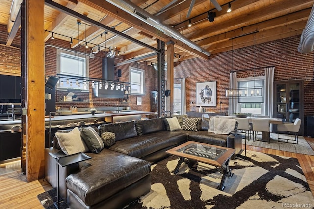 living room featuring a high ceiling, brick wall, wooden ceiling, and light hardwood / wood-style floors