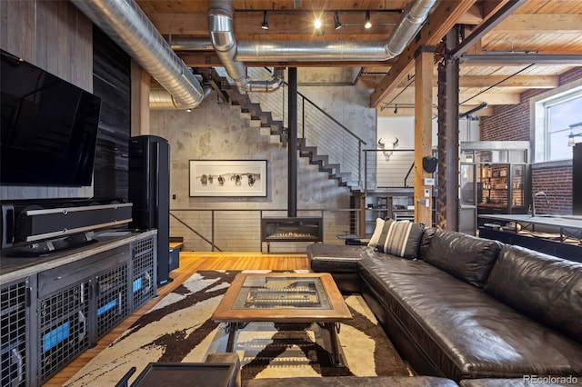 living room featuring hardwood / wood-style floors, sink, a wood stove, a high ceiling, and track lighting