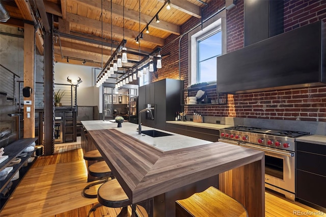 kitchen featuring high end appliances, wooden ceiling, light wood-type flooring, and wall chimney range hood