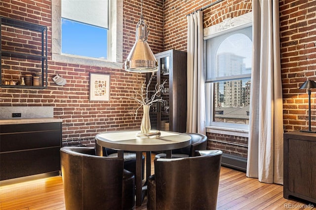 dining space with brick wall and light hardwood / wood-style floors