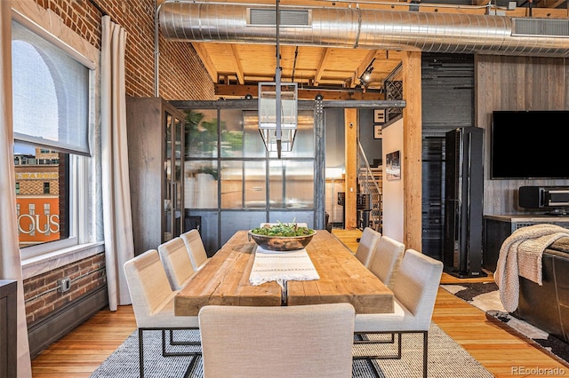 dining area with light hardwood / wood-style flooring, a baseboard radiator, and brick wall