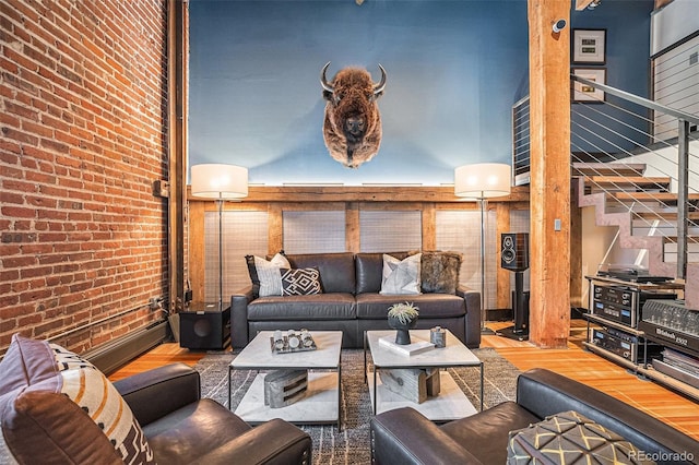 living room featuring brick wall, wood-type flooring, and a towering ceiling