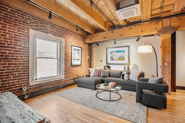 living room featuring rail lighting, brick wall, hardwood / wood-style floors, and beam ceiling