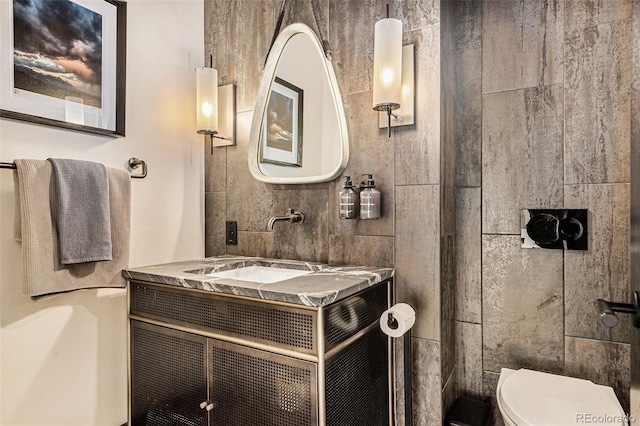 bathroom featuring vanity, tile walls, and toilet