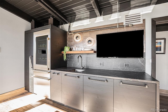 bar featuring sink, backsplash, light hardwood / wood-style floors, and beamed ceiling