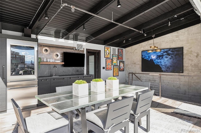 dining area with sink, beam ceiling, light hardwood / wood-style flooring, and track lighting