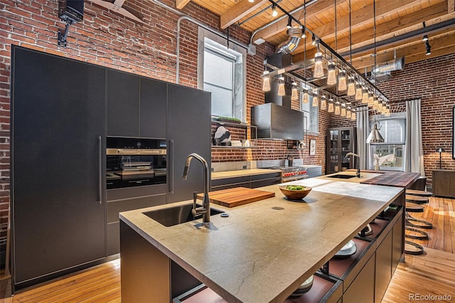 kitchen featuring a large island, sink, wooden ceiling, and brick wall