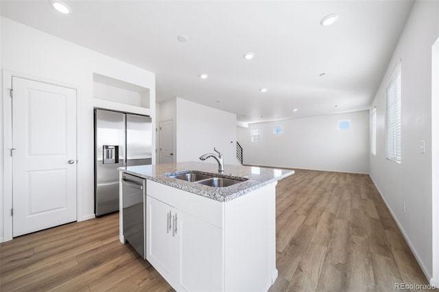 3869 N Shawnee St, Aurora, CO 80019 - kitchen featuring stainless steel appliances, a sink, light stone countertops, a center island with sink, and white cabinetry
