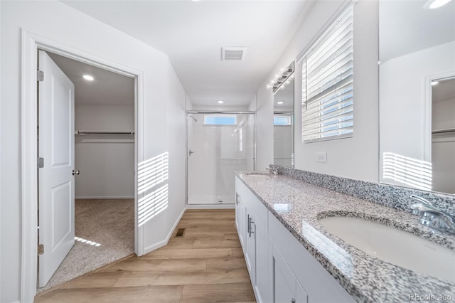 3869 N Shawnee St, Aurora, CO 80019 - bathroom featuring a shower stall, wood finished floors, double vanity, a spacious closet, and recessed lighting