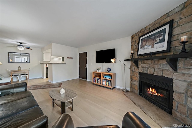 8335 Fairmount Dr Unit 2-105, Denver, CO 80247 - living room featuring a stone fireplace, light wood-style floors, a ceiling fan, and baseboards