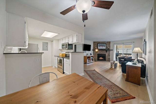 8335 Fairmount Dr Unit 2-105, Denver, CO 80247 - dining area with light wood-style floors, a fireplace, ceiling fan, electric panel, and baseboards