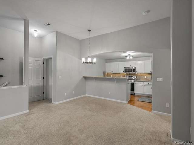 7131 S Wenatchee Way Unit C, Aurora, CO 80016 - kitchen featuring stainless steel appliances, light colored carpet, white cabinets, a peninsula, and a breakfast bar