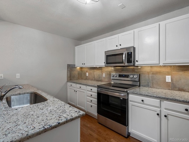 7131 S Wenatchee Way Unit C, Aurora, CO 80016 - kitchen featuring appliances with stainless steel finishes, white cabinets, wood finished floors, backsplash, and light stone countertops