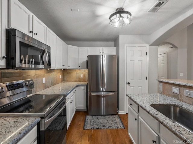 7131 S Wenatchee Way Unit C, Aurora, CO 80016 - kitchen featuring appliances with stainless steel finishes, dark wood-type flooring, white cabinetry, and backsplash