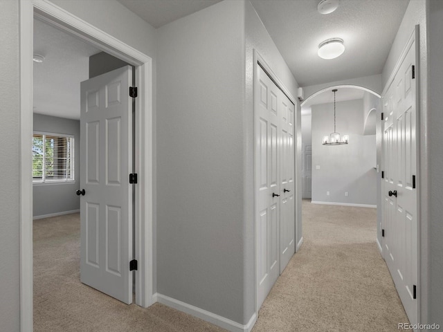 7131 S Wenatchee Way Unit C, Aurora, CO 80016 - corridor featuring light carpet, arched walkways, and a chandelier