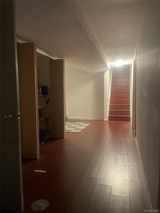 hallway with a textured ceiling and hardwood / wood-style flooring