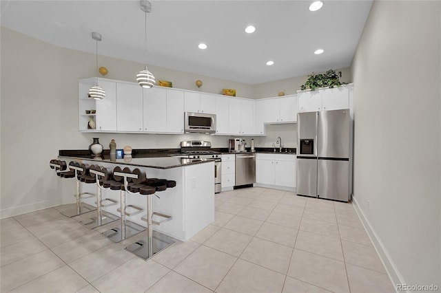 kitchen featuring kitchen peninsula, white cabinetry, hanging light fixtures, and appliances with stainless steel finishes