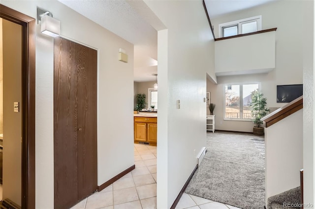 corridor featuring light carpet, visible vents, baseboards, and light tile patterned flooring