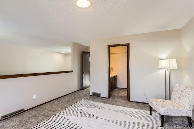 interior space with baseboards, visible vents, a textured ceiling, and light colored carpet